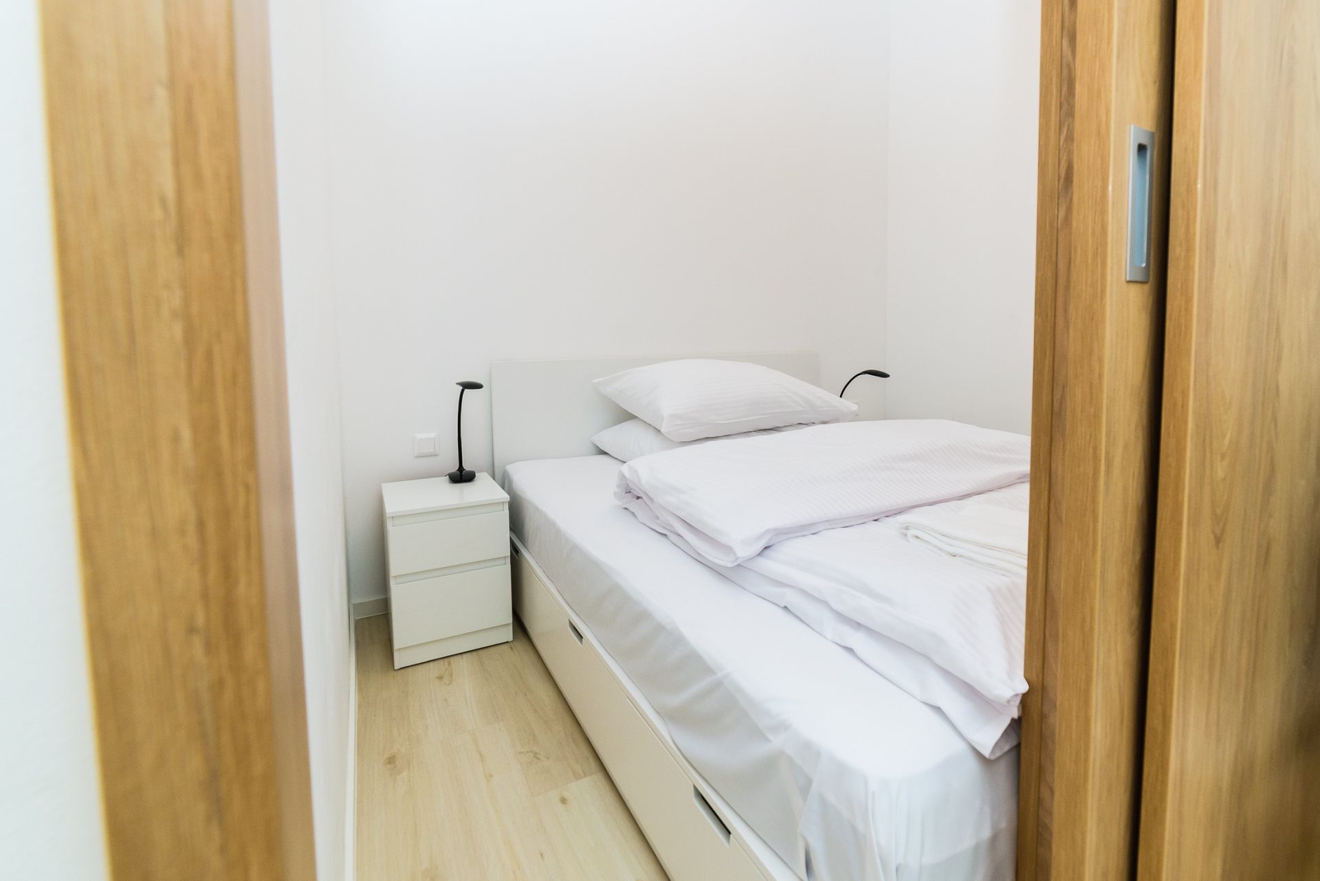 Oddelená posteľ šikovnou drevenou priečkou s posuvnou stenou.